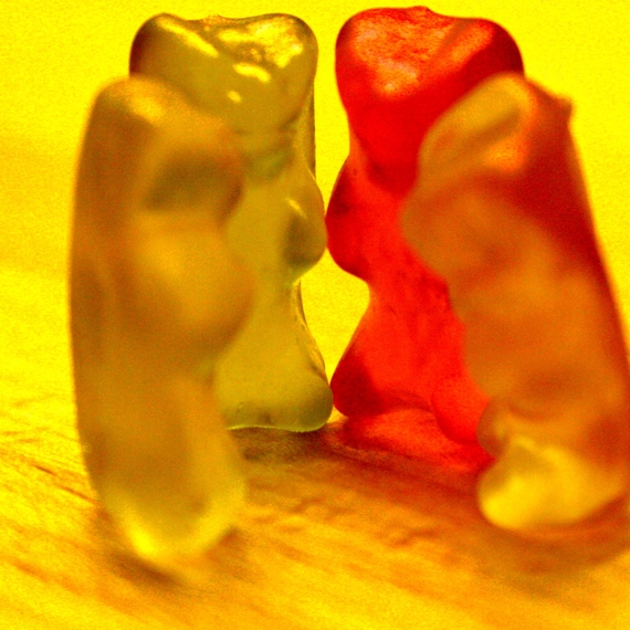Das Bild zeigt vier Gummibärchen, die in einem Kreis stehen. / The image shows four gummi bears standing in a circle.